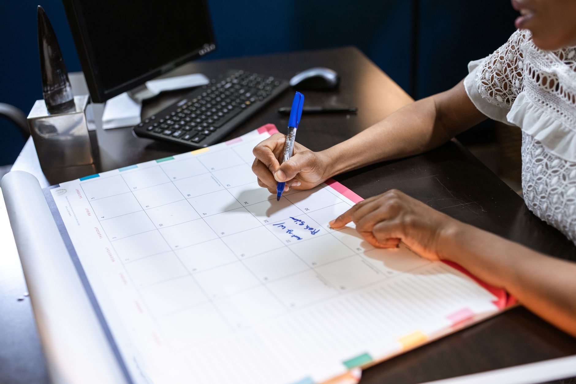 Person writing important Medicare enrollment timeline dates in a desk calendar
