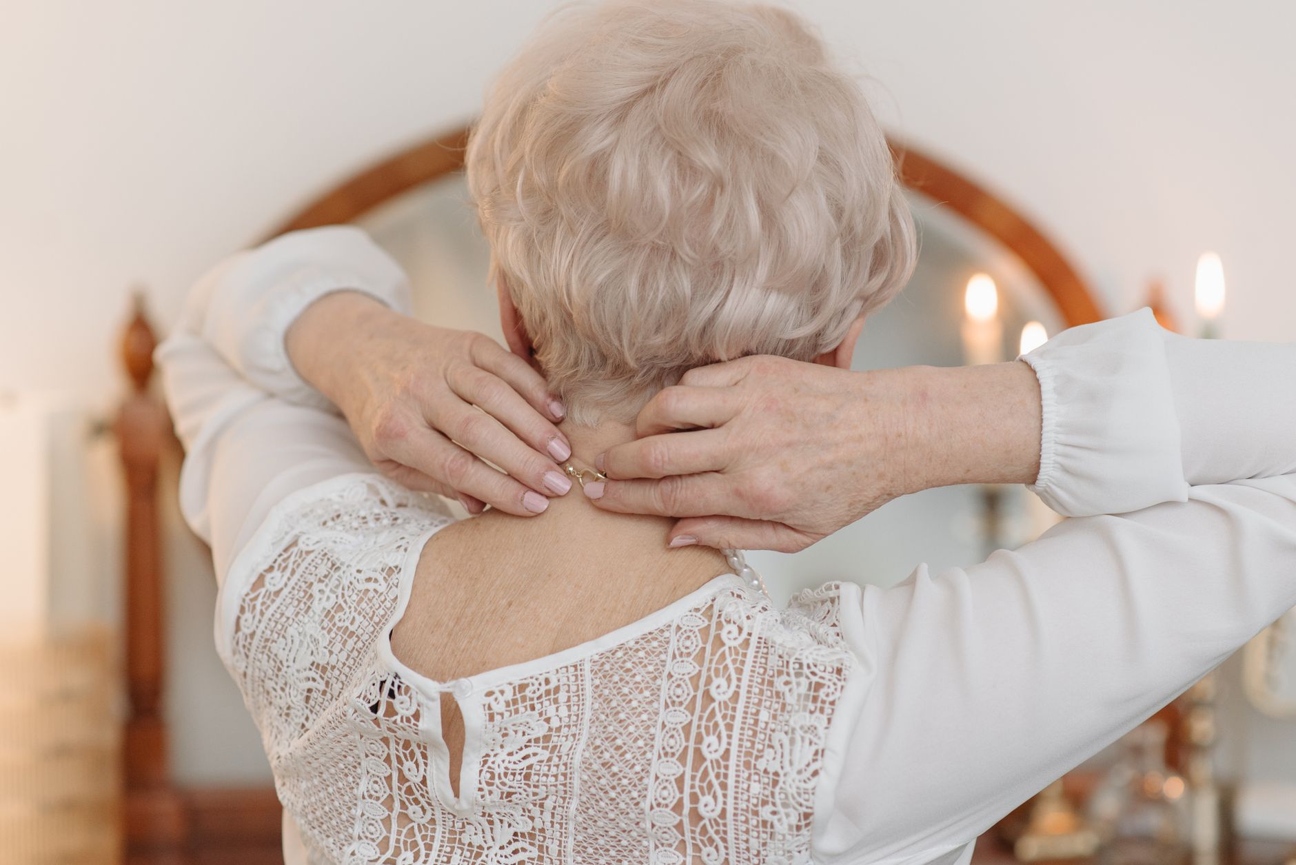 Close-up of an elderly woman adjusting a necklace, representing a wearable medical alert device