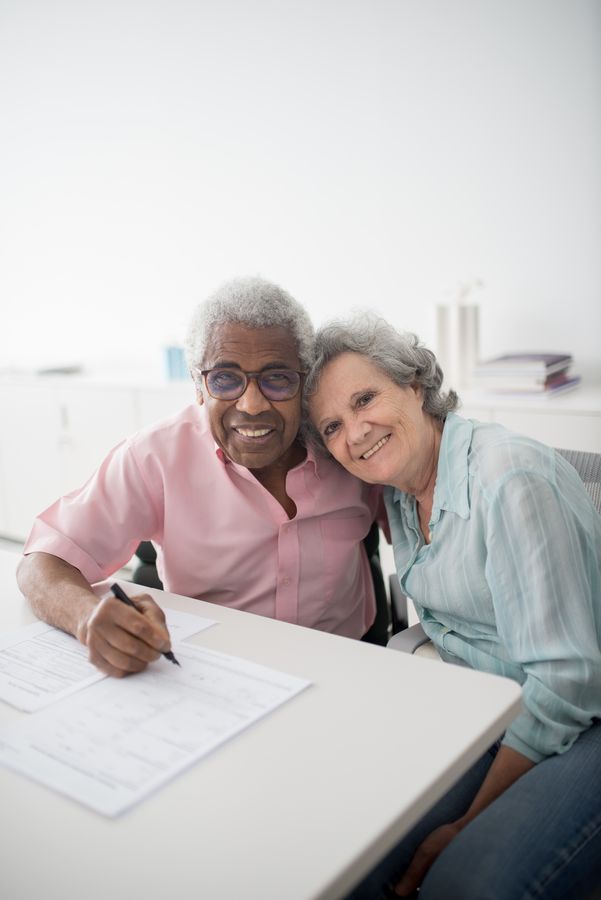 Happy couple sitting at a desk reviewing health insurance documents before turning 65