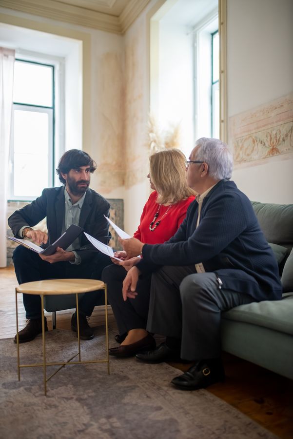 Financial advisor discussing life insurance documents with a senior couple in their living room